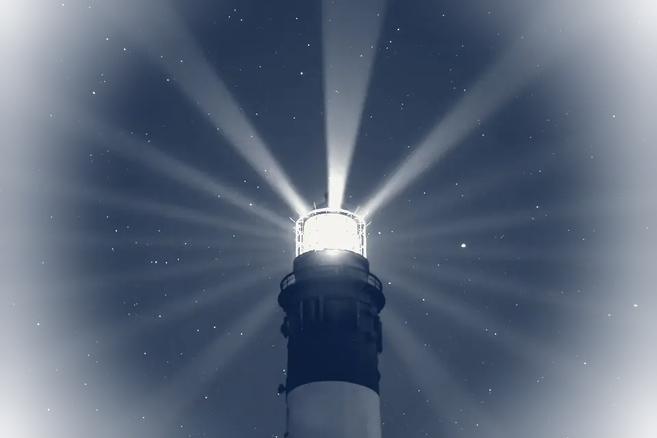 Phare projetant un faisceau lumineux sous un ciel étoilé